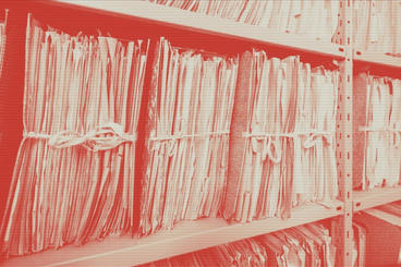 Bundled papers sitting on shelves. The image has a red filter on it.